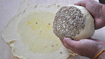 posizionala sul disco in modo che la parte con i semi sia sulla parte spennellata d’olio